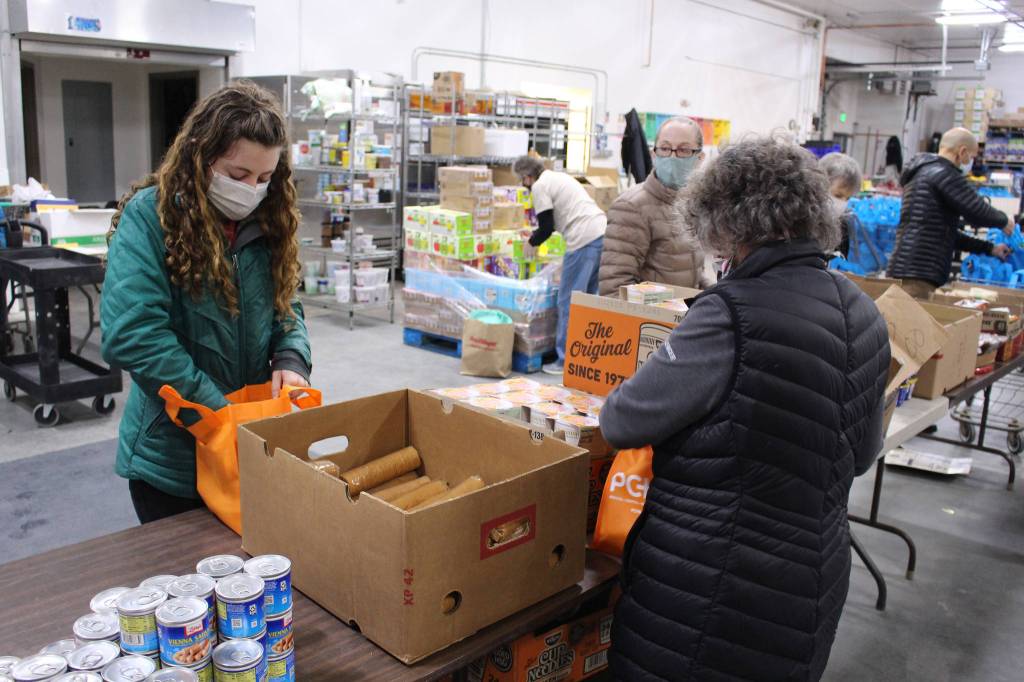 Volunteers Heather Schaefer, Alecia Gottlob and Peggy Rogers prepare bags of shelf-stable food to be distributed during Project Homeless Connect at the Kenai Peninsula Food Bank in Soldotna, Alaska on Jan. 23, 2021. (Photo by Brian Mazurek/Peninsula Clarion)