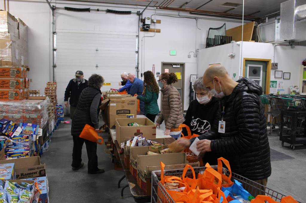 Volunteers prepare bags of shelf stable food to distribute during the upcoming Project Homeless Connect event at the Kenai Peninsula Food Bank in Soldotna, Alaska on Jan. 23, 2021. Pictured, from left: Billy Kelley, Peggy Rogers, Troy Castimore, Pat Young, Heather Schaefer, Alecia Gottlob, Bobbi Stelljes and Frank Alioto. (Photo by Brian Mazurek/Peninsula Clarion)