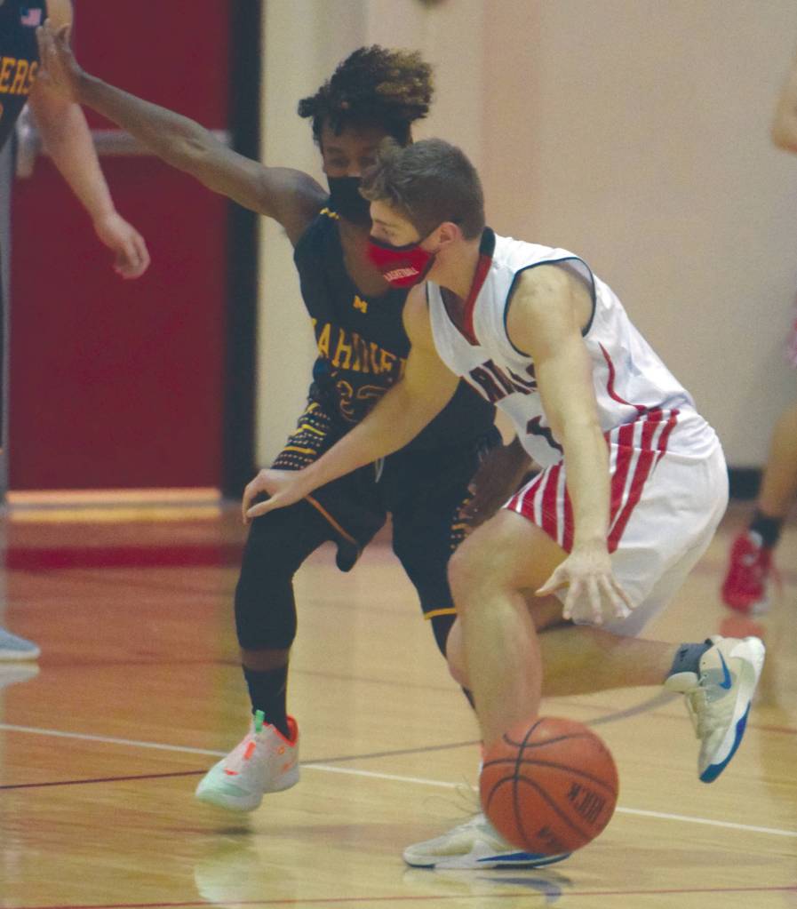 Kenai Centrals Maison Dunham drives on Homers Eyoab Knapp on Thursday, Jan. 28, 2021, at Kenai Central High School in Kenai, Alaska. (Photo by Jeff Helminiak/Peninsula Clarion)