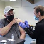 Ty Smith, paramedic/firefighter with the Nikiski Fire Department, administers the first dose of the Moderna COVID-19 vaccine to Ronald Huntsman of Nikiski during a clinic at the Nikiski Community Recreation Center on Jan. 30, 2021. (Photo by Brian Mazurek/Peninsula Clarion)