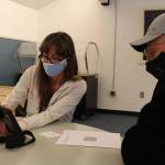 Julie Denison, member of the Kenai Peninsula Boroughs Incident Management Team, helps Ronald Huntsman of Nikiski schedule his second round of the Moderna COVID-19 vaccine during a vaccine clinic at the Nikiski Community Recreation Center on Jan. 30, 2021. (Photo by Brian Mazurek/Peninsula Clarion)