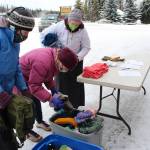 Project Homeless Connect volunteers help Arlene Jasky, center, pick out hats and gloves for a friend during a Project Homeless Connect event at the Sterling Senior Citizens Center in Sterling, Alaska, on Feb. 2, 2021. (Photo by Brian Mazurek/Peninsula Clarion)