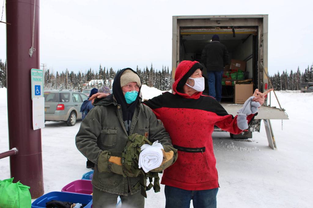 Bill Kelley, left, hands a backpack full of supplies and towels to Dale Curtis, right, during a Project Homeless Connect Event at the Sterling Senior Citizens Center in Sterling, Alaska, on Feb. 2, 2021. (Photo by Brian Mazurek/Peninsula Clarion)