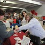 Robin Hahn, left, of Soldotna buys some hot cocoa bombs from Sherian Soares, right, and Ashley Soares, center, owners of Bennys Sweets and Beyond, at a Valentines Bazaar in Soldotna, Alaska on Feb. 6, 2021. (Photo by Brian Mazurek/Peninsula Clarion)