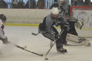 Soldotna's Dylan Walton keeps the puck away from Kenai Central's Riley Graves in front of SoHi goalie Ayden See on Saturday, Feb. 13, 2021, at the Kenai Multi-Purpose Facility in Kenai, Alaska. (Photo by Jeff Helminiak/Peninsula Clarion)