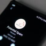 A phone screen displays a message warning of a potential spam call. Alaska Department of Public Safety warns of a new scam involving text messages sent to the family members of missing people. (Ben Hohenstatt / Juneau Empire)