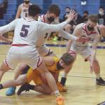 Ninilchiks Cole Hadro is surrounded by Noah Cruz, Daniel Bennett and Tim Bennett of Lumen Christi on Friday, March 19, 2021, in the Peninsula Conference championship game at Soldotna High School in Soldotna, Alaska. (Photo by Jeff Helminiak/Peninsula Clarion)