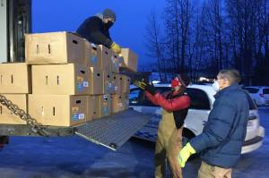 Jeff Helminiak/Peninsula Clarion
Todd Duwe hands a food box to Brad Nyquist as Mark Larson looks on Dec. 22, 2020, at Christ Lutheran Church in Soldotna. The church volunteers were distributing food from the United States Department of Agricultures Farmers to Families Food Box Program, delivered by the Kenai Peninsula Food Bank. The food bank saw a surge in demand last year due to the coronavirus pandemic.