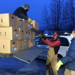 Todd Duwe hands a food box to Brad Nyquist as Mark Larson looks on Tuesday, Dec. 22, 2020, at Christ Lutheran Church in Soldotna, Alaska. The church volunteers were distributing food from the United States Department of Agricultures Farmers to Families Food Box Program, delivered by the Kenai Peninsula Food Bank. The food bank saw a surge in demand last year due to the coronavirus pandemic. (Photo by Jeff Helminiak/Peninsula Clarion)