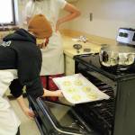 Izzy Dye pops a batch of pretzels into the oven during a high school food and nutrition class at Homer High School in Homer, Alaska. (Photo by Katelyn Engebretsen/Homer High Yearbook)