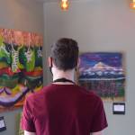 Samuel Anderson examines artwork up for bid while on shift at Veronicas Cafe on April 7, 2021. The Kenai Fine Art Center and KDLL Public Radio are auctioning off local art through the month of April. (Photo by Camille Botello/Peninsula Clarion)