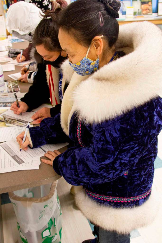 In this photo, provided by Norton Sound Health Corp., are Joey Annogiyuk, left, and Miriam Toolie signing up to receive the Pfizer vaccine at the Savoonga Clinic in Savoonga, Alaska, on Jan. 14, 2021. Some of Alaskas highest vaccination rates among those 16 or older have been in some of its remotest, hardest-to-access communities, where the toll of past flu or tuberculosis outbreaks hasnt been forgotten. (Reba Lean/Norton Sound Health Corp. via AP)