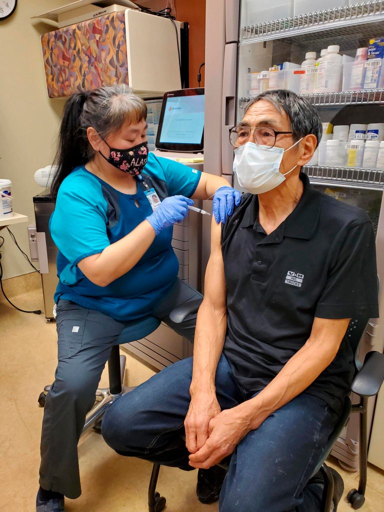 In this photo provided by Norton Sound Health Corp., is nurse LaVerne Saccheus providing a vaccination to Unalakleet elder Joseph Nupid Katchatag in Unalakleet, Alaska, on Dec. 23, 2020. Alaskas highest vaccination rates among those 16 or older have been in some of its remotest, hardest-to-access communities, where the toll of past flu or tuberculosis outbreaks hasnt been forgotten. (Carol Charles/Norton Sound Health Corp. via AP)