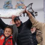 Andrew Marley, the 2021 Homer Winter King Salmon Tournament winner, at left, holds his prize winning 25.62-pound white king salmon on Saturday, April 17, 2021, on the Homer Spit in Homer, Alaska. Helping him are his father, Jay Marley, center, and older brother Weston Marley, right. The family team included Erica Marley, not shown, all fishing on the Fly Dough. (Photo by Michael Armstrong/Homer News)