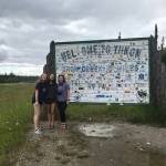 From left to right: Camille Botello, Emma Schoonover and Grace Thompson-Johnston stand in front of a sign welcoming them to the Yukon territory in Canada as they make their way up the Alaska Highway on July 16, 2020. (Photo provided)