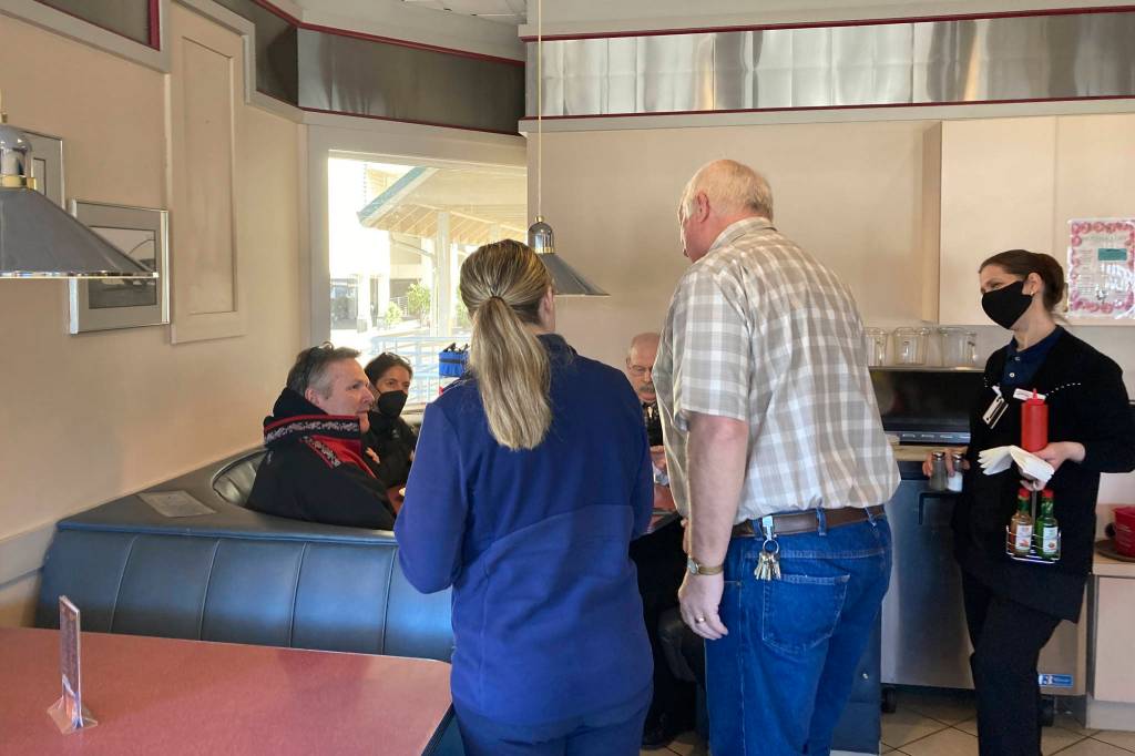 John Judson, standing second from right, and his daughter, Jasmine Pattison, standing in center, stop to greet Gov. Mike Dunleavy, seated at left, at The Landing Restaurant in Ketchikan, Alaska, on Thursday, April 22, 2021. Dunleavy visited Ketchikan as part of a one-day trip in southeast Alaska. Also seated at the table are Dr. Anne Zink, the states chief medical officer, and Alaska state Sen. Bert Stedman. (AP Photo/Becky Bohrer)
