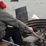 Ventis Plume tends to his fire at the end of his 10-day setnet trip at the Kasilof River State Recreational Site in Kasilof, Alaska, on June 25, 2021. (Camille Botello / Peninsula Clarion)