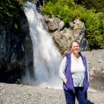 In June 2021, Stephanie Presley, program lead for the Seward-Bear Creek Flood Service Area, stands in front of the Lowell Creek waterfall, which is caused by one of Sewards most important flood mitigation efforts to divert Lowell Creek away from the center of town and tunnel it directly into nearby Resurrection Bay. (Young Kim for The Hechinger Report)