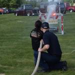 An official with the fire department teaches kids how to extinguish flames with the firehose during the carnival games at the annual Fourth of July celebration in Kenai on July 4, 2021. (Camille Botello / Peninsula Clarion)