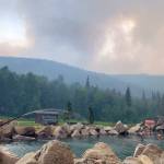 Alaska Division of Forestry via Associated Press
Smoke from the Munson Creek Fire rises behind the Chena Hot Springs Resort as guests watch from the outdoor rock pool near Fairbanks, on Monday. Authorities on Monday advised residents and guests to evacuate immediately after a nearby wildfire intensified. The Fairbanks North Star Borough issued the evacuation order when the fire reached a point less than a mile behind Chena Hot Springs.