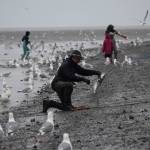 A dipnetter wrangles a salmon North Kenai Beach on Saturday, July 10, 2021. (Camille Botello / Peninsula Clarion)
