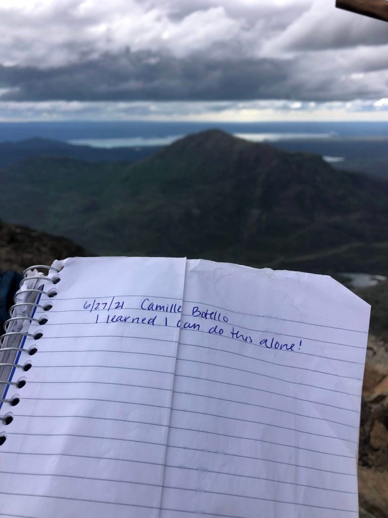 Camille Botello signs the lock-box book at the peak of the Skyline Trail on June 27, 2021. (Camille Botello / Peninsula Clarion)