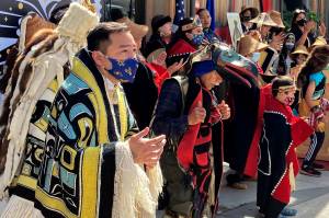 Rico Worl, foreground left, dances during a ceremony on Friday, July 30, 2021, in Juneau, Alaska, that marked the release of a stamp he created for the U.S. Postal Service. Worl, an Alaska Native artist, has said he hopes the Raven Story stamp will be a gateway for people to learn about his Tlingit culture. (AP Photo/Becky Bohrer)