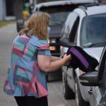 Joanne Jenkins distributes backpacks and school supplies to a line of cars at the Peninsula Community Health Services KidFest event on Wednesday, Aug. 4, 2021 in Kenai, Alaska. (Camille Botello/Peninsula Clarion)