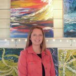 Tracy Hansen poses for a photo in front of her paintings at her Ocean Drive shop, 59 North, on Tuesday, Aug. 10, 2021, in Homer, Alaska. (Photo by Michael Armstrong/Homer News)
