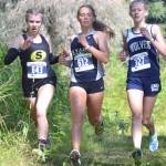 Soldotnas Jordan Strausbaugh races to 17th place in the girls varsity race at the Ted McKenney XC Invitational on Saturday, Aug. 21, 2021, at Tsalteshi Trails just outside of Soldotna, Alaska. We run for Ted is written on Strausbaughs thigh in honor of former Soldotna coach Ted McKenney. Strausbaugh runs with Souths Elizabeth Page and Eagle Rivers Ava Trembath. (Photo by Jeff Helminiak/Peninsula Clarion)