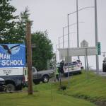 Parents on Monday, Aug. 23, 2021, pick up students at Chapman School in Anchor Point, Alaska, after a shooting about a half mile north on the Sterling Highway in which an Alaska State Trooper was shot. The school was on lockdown while troopers searched for the alleged shooter, Bret Herrick, 60. An Alaska State Trooper stands by. (Photo by Michael Armstrong/Homer News)