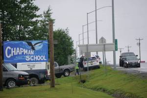 Parents on Monday, Aug. 23, 2021, pick up students at Chapman School in Anchor Point, Alaska, after a shooting about a half mile north on the Sterling Highway in which an Alaska State Trooper was shot. The school was on lockdown while troopers searched for the alleged shooter, Bret Herrick, 60. An Alaska State Trooper stands by. (Photo by Michael Armstrong/Homer News)