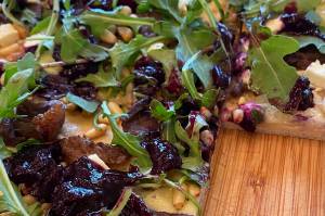 Arugula, pine nuts, and the blueberry relish top meats and homemade pizza dough. (Photo by Tress Dale/Peninsula Clarion)