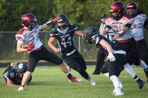 Houston running back Cody Wyrick tries to get past Nikiski's Truit McCaughey and Christian Caddock on Friday, Aug. 27, 2021, at Nikiski High School in Nikiski, Alaska. (Photo by Jeff Helminiak/Peninsula Clarion)