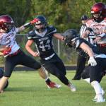 Houston running back Cody Wyrick tries to get past Nikiskis Truit McCaughey and Christian Caddock on Friday, Aug. 27, 2021, at Nikiski High School in Nikiski, Alaska. (Photo by Jeff Helminiak/Peninsula Clarion)