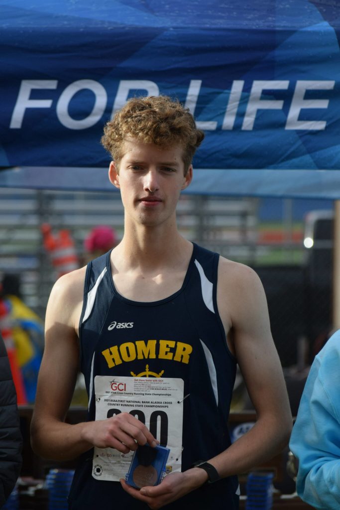 Seamus McDonough of Homer gets a medal at the Division II state cross country championship at Bartlett High School in Anchorage, Alaska on Saturday, Oct. 9, 2021 for his ninth place finish. (Camille Botello/Peninsula Clarion)