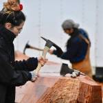 University of Alaska Student Skaydu.û Jules, carves a red cedar log under the supervision of Tlingit master carver Wayne Price in the parking lot of Angoon High School on Tuesday, Oct. 26, 2021. Jules a member of the Teslin Tlingit Council, a self-governing First Nation based in Teslin in Southern Yukon Territory, Canada, and said she wants to become a Tlingit language teacher. (Peter Segall / Juneau Empire)