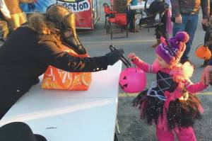 Amelie Bignell, of Soldotna, drops a treat in the bucket of Hayden Jones, of Soldotna, on Saturday, Oct. 31, 2020, at a trunk-or-treat event at Orca Theatre on Kalifornsky Beach Road in Alaska. Jones was dressed as Vampirina. (Photo by Jeff Helminiak/Peninsula Clarion)