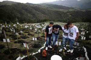 Relatives of Luis Enrique Rodriguez, who died of COVID-19, visit where he was buried on a hill at the El Pajonal de Cogua Natural Reserve, in Cogua, north of Bogota, Colombia, Monday, Oct. 25, 2021. Rodriguez died May 14, 2021. Relatives bury the ashes of their loved ones who died of coronavirus and plant a tree in their memory. (AP Photo/Ivan Valencia)