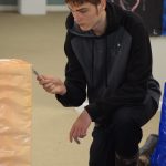 Jacob Bayhi paints a podium for the Kenai Alternative High Schools mural installation at the Kenai Art Center on Tuesday, Nov. 9, 2021. (Camille Botello/Peninsula Clarion)