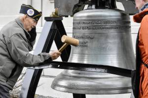 U.S. Coast Guard veteran Jim Wilcox Sr. strikes a replica of the Liberty Bell in front of the Alaska State Capitol on Nov. 11, 2021, during an Armistice Day celebration hosted by Veterans for Peace. The local VFP chapter holds bell ringings annually on Nov. 11, which is also Veterans Day, to remember all the lives lost to war and to call for world peace. (Peter Segall / Juneau Empire)