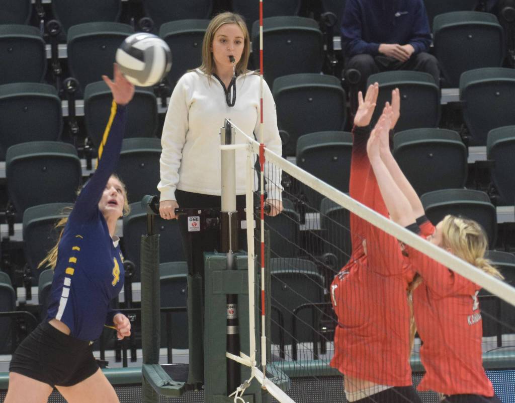 Homer's Gracie Gummer goes up for a kill against Kenai blockers Calani Holmes and Emma Beck during the 3A state volleyball consolation game at the Alaska Airlines Center in Anchorage, Alaska, on Saturday, Nov. 13, 2021. (Camille Botello/Peninsula Clarion)