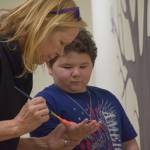 Carolyn Massey paints 10-year-old Kenny Smiths hand to add to the helping hands tree at the Childrens Advocacy Center on Tuesday, Nov. 16, 2021, in Kenai, Alaska. (Camille Botello/Peninsula Clarion)