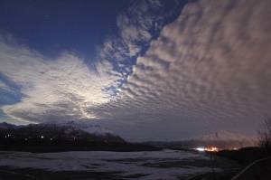 Clouds over the sky over Lazy Mountain and the Matanuska River on March 23, 2016, in Palmer, Alaska. Lights from downtown Palmer and Pioneer Peak can be seen in the lower right. Some critics say a new map of state political boundaries drawn following the last Census short-changes the fast-growing area north of Anchorage seen as a hotbed of conservatism. (AP Photo/Dan Joling, File)