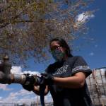 Raynelle Hoskie attaches a hose to a water pump to fill tanks in her truck outside a tribal office on the Navajo reservation in Tuba City, Ariz., on April 20, 2020. A massive infrastructure bill that President Joe Biden signed this week includes billions of dollars to address long-standing issues with water and sanitation on tribal land. (AP Photo/Carolyn Kaster, File)