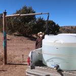 Phillip Yazzie waits for a water drum in the back of his pickup truck to be filled in Teesto, Ariz., on the Navajo Nation, on Feb. 11, 2021. A massive infrastructure bill that President Joe Biden signed this week includes billions of dollars to address long-standing issues with water and sanitation on tribal land. (AP Photo/Felicia Fonseca, File)