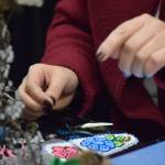 Michelle Ravenmoon sews a beaded artisan product at the Soldotna Holiday Bazaar at the Soldotna Regional Sports Complex on Saturday, Nov. 20, 2021. (Camille Botello/Peninsula Clarion)