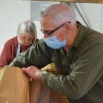 Kenai Senior Center volunteer Carol Freas, left, and driver Don Erwin prepare to-go Thanksgiving meals at the center on Tuesday, Nov. 23, 2021. (Camille Botello/Peninsula Clarion)