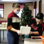 Kathy Heindl (right) loads cranberry sauce into a tray assembled by Regan Evans (left) at a drive-through Thanksgiving meal event hosted by the Salvation Army on Thursday, Nov. 25, 2021 in Kenai, Alaska. (Ashlyn OHara/Peninsula Clarion)