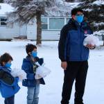 Carter Kyle (left), Lincoln Kyle (center) and Brandon Kyle (right) hand off Thanksgiving meals at a drive through event hosted by the Salvation Army on Thursday, Nov. 25, 2021 in Kenai, Alaska. (Ashlyn OHara/Peninsula Clarion)
